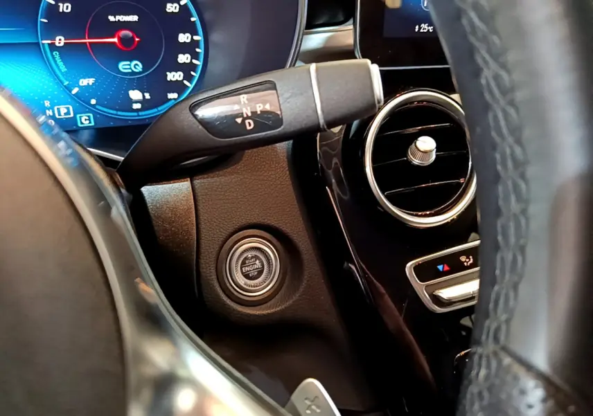 Détail intérieur côté gauche du tableau de bord du Mercedes GLC 300 E AMG Line avec bouton démarrage et levier de vitesses.