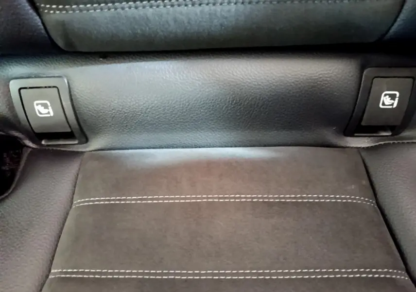 Gros plan sur la commande de rabattement des sièges arrière en cuir noir avec surpiqûres blanches dans un Mercedes GLC 300 E AMG Line.