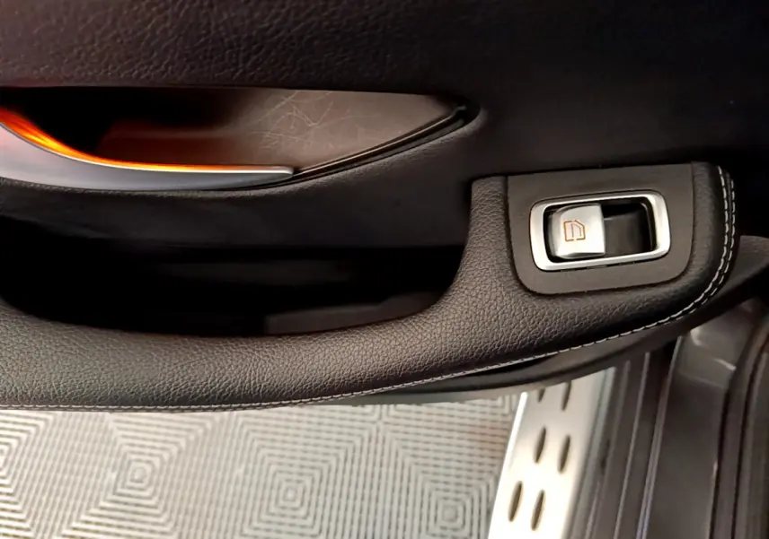 Gros plan sur la poignée de porte intérieure en cuir noir avec bouton de lève-vitre du Mercedes GLC 300 E AMG Line.
