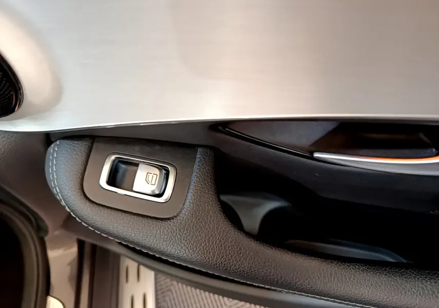 Gros plan sur la commande de lève-vitre côté conducteur en cuir noir et insert aluminium du Mercedes GLC 300 E AMG Line 2021.