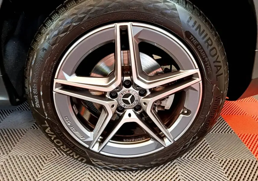 Gros plan sur la jante AMG étoile argentée et pneu Uniroyal d'un Mercedes GLC 300 E hybride gris foncé.