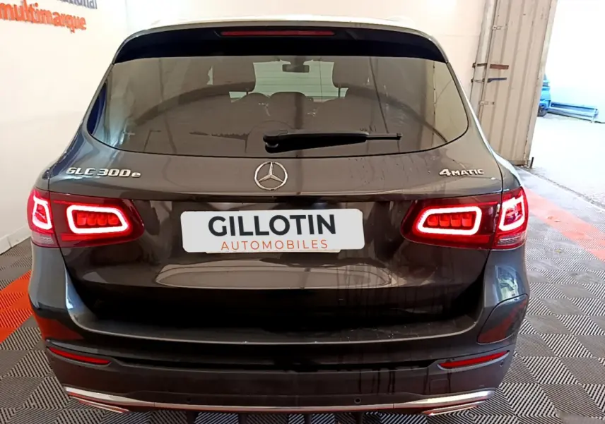 Vue arrière d'un Mercedes GLC 300 e AMG Line gris foncé avec feux LED allumés et logo 4MATIC visible