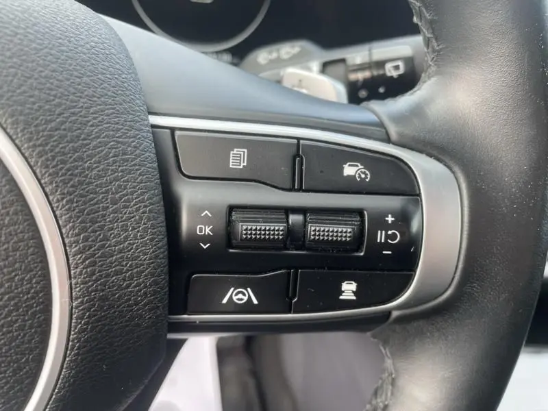 Gros plan sur les commandes du volant côté droit du Kia Sportage 2022, avec boutons de régulateur de vitesse et aides à la conduite.
