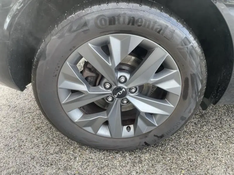 Gros plan sur la roue avant droite du KIA SPORTAGE 2022 vert métal, avec jante alliage et pneu Continental visible.