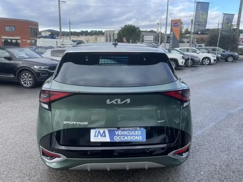 Vue arrière d'un Kia Sportage vert métal 2022 avec logo moderne et feux arrière étirés, sur parking extérieur.