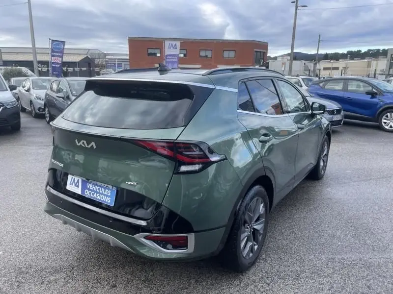 Vue 3/4 arrière droite d’un Kia Sportage vert métal 2022 avec toit noir et feux arrière LED distinctifs.