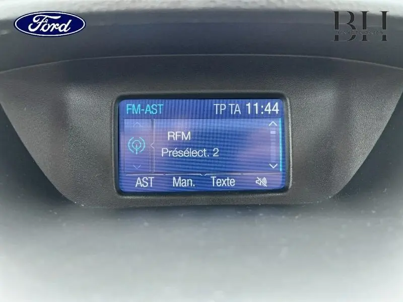 Écran multifonction bleu affichant la radio FM dans l'habitacle du Ford EcoSport Titanium gris Smoke, vue de face.