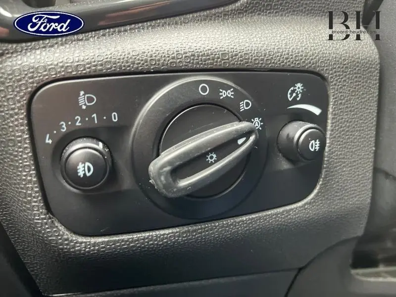 Gros plan sur la commande des phares noire du Ford Ecosport 2017, avec réglage des feux et antibrouillard.