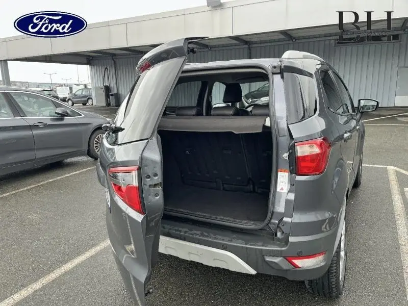 Vue 3/4 arrière droite d'un Ford EcoSport 1.5 TDCi gris Smoke avec hayon ouvert montrant le coffre vide.