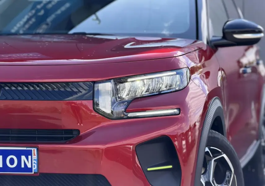 Gros plan sur le 3/4 avant droit de la Citroën C3 Rouge Elixir avec ses phares LED allumés et jantes alliage visibles.