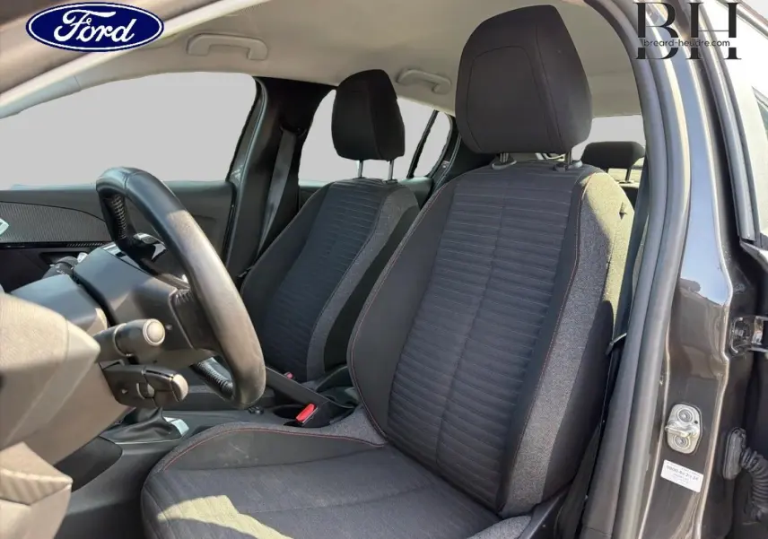 Vue intérieure côté conducteur de la Peugeot 208 1.5 BlueHDi gris Platinium, montrant les sièges avant et le volant.