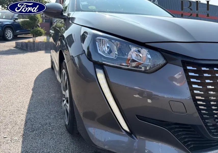 Vue 3/4 avant gauche d'une Peugeot 208 gris Platinium avec phares et calandre distinctifs visibles.