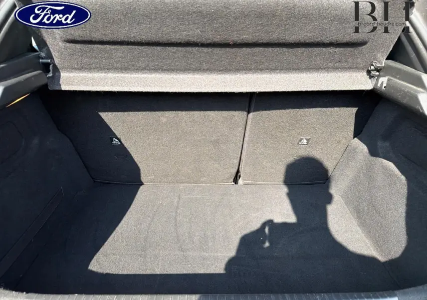Coffre ouvert d’une Peugeot 208 gris Platinium, montrant l’espace de chargement intérieur vide et la tablette cache-bagages.