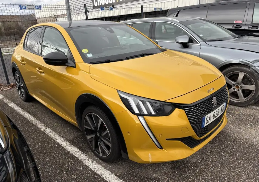 Peugeot 208 GT jaune vue 3/4 avant droit, avec calandre noire et feux LED en forme de griffes.