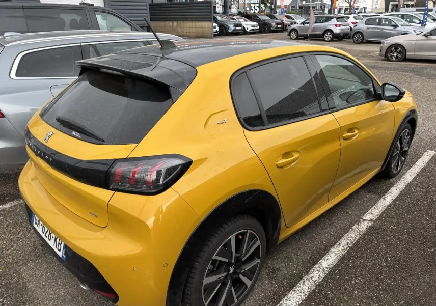 Peugeot 208 GT jaune vue 3/4 arrière droit, toit noir et jantes alliage distinctives, stationnée en extérieur.