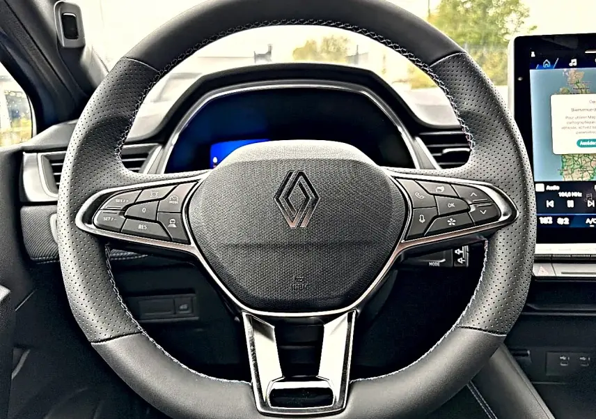 Vue rapprochée du volant multifonction noir de la Renault Symbioz 2026 avec écran tactile en arrière-plan.