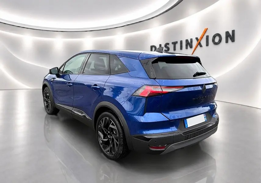 Vue 3/4 arrière droite du Renault Symbioz 2026 bleu iron avec jantes noires et feux arrière LED distinctifs.