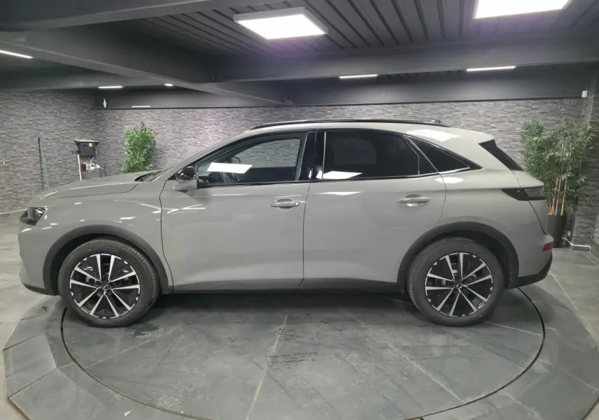 Vue de profil côté gauche du DS7 Crossback gris métallisé, avec jantes alliage noires et toit panoramique.