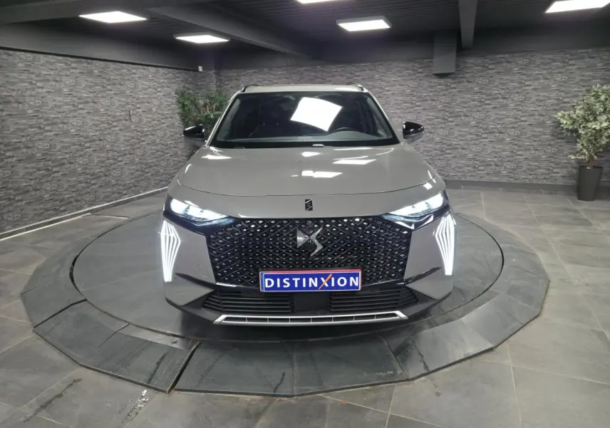 Vue frontale d'un DS7 Crossback gris avec calandre noire à motif diamant et feux LED verticaux allumés.