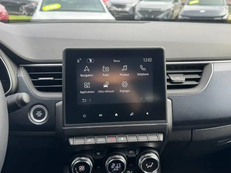 Tableau de bord du Renault Arkana 2025 avec écran tactile central et commandes de climatisation en vue frontale rapprochée.