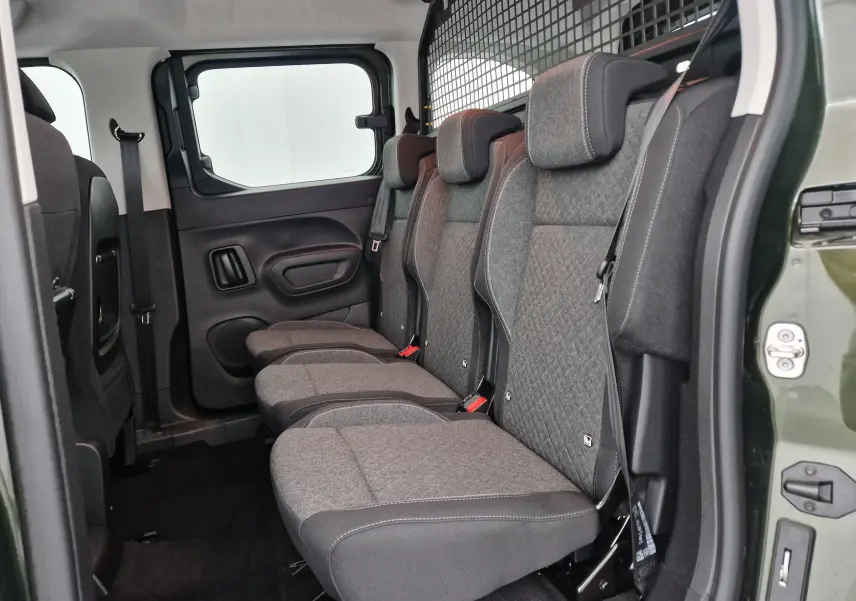 Vue latérale des trois sièges individuels arrière gris dans l'habitacle d'un Opel Combo Life vert Sirkka avec grille de séparation.