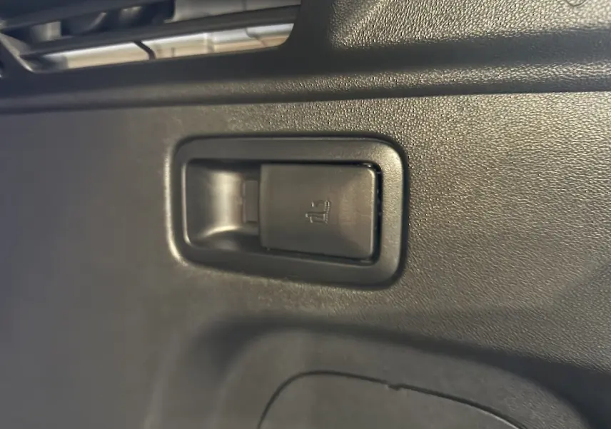 Gros plan sur la commande de rabattement des sièges arrière dans l’habitacle noir de l’Opel Grandland X blanc hybride rechargeable.