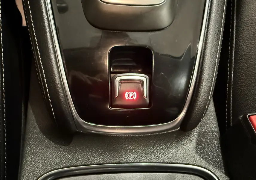 Gros plan sur le bouton de frein à main électronique rouge dans la console centrale de l’Opel Grandland X hybride rechargeable.