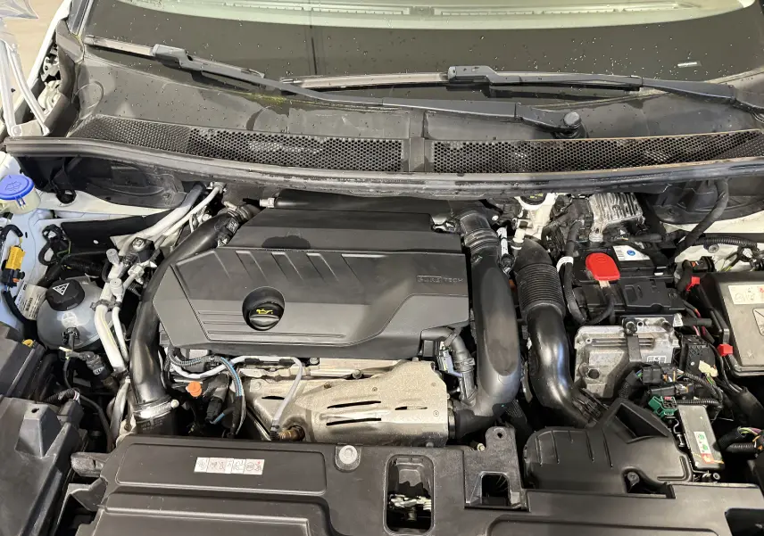 Vue rapprochée du moteur de l’Opel Grandland X blanc, mettant en valeur le compartiment moteur propre et organisé.