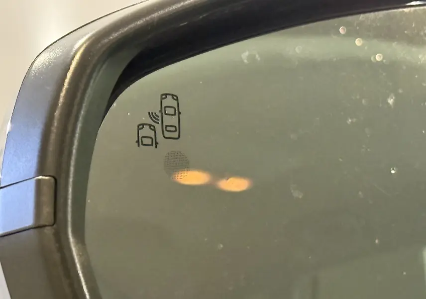 Gros plan sur le rétroviseur côté gauche de l’Opel Grandland X blanc, avec l’icône d’alerte d’angle mort visible.