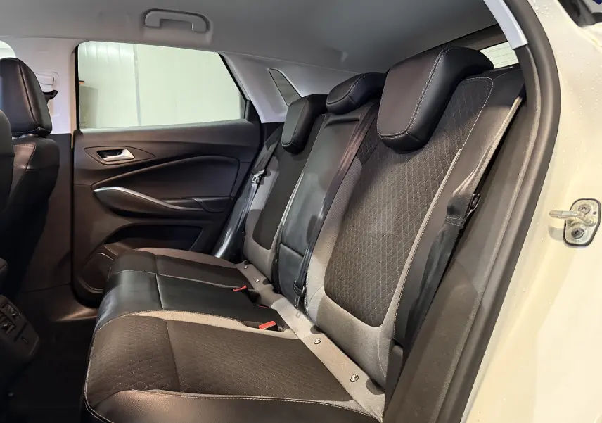 Vue intérieure côté droit des sièges arrière noirs et gris du Opel Grandland X blanc, montrant les appuie-têtes et la portière ouverte.