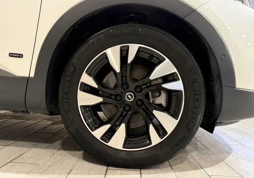 Gros plan sur la roue avant droite blanche d’un Opel Grandland X hybride avec jante noire et argentée.