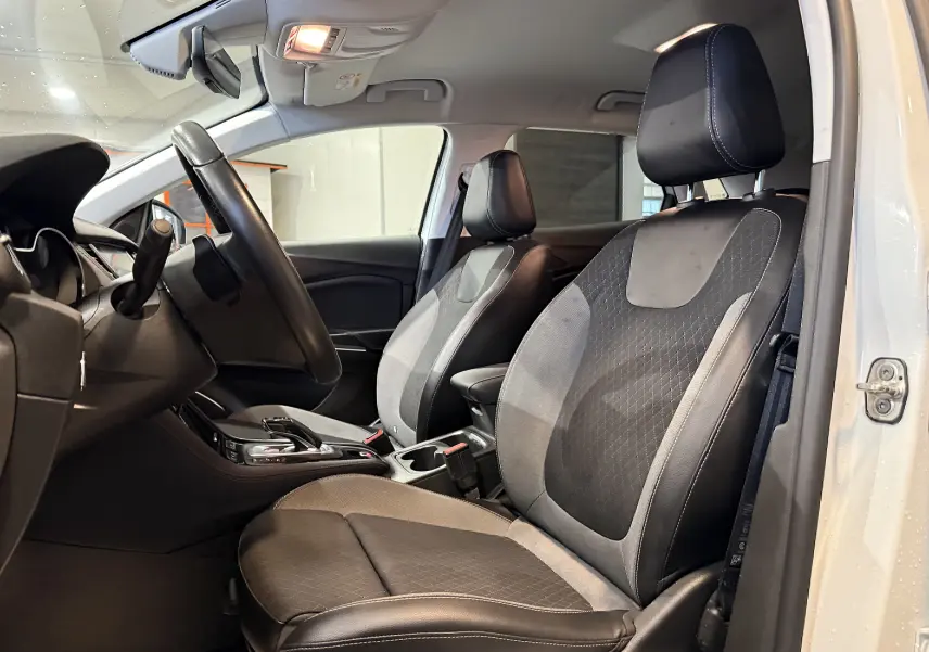 Vue intérieure côté conducteur de l'Opel Grandland X blanc, sièges avant en cuir noir et tissu gris, volant visible.