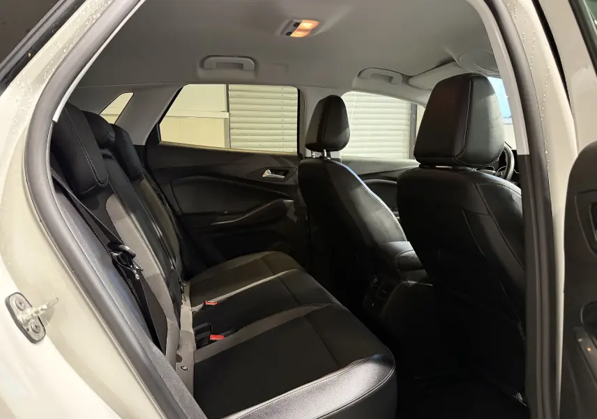 Vue intérieure arrière côté gauche de l’Opel Grandland X blanc, montrant les sièges noirs en cuir et tissu.