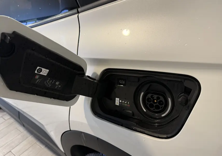Prise de recharge ouverte côté gauche d’un Opel Grandland X blanc hybride rechargeable, vue rapprochée sur le port de charge.