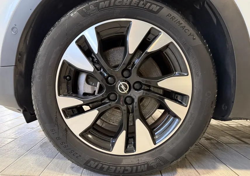 Gros plan sur la jante alliage bicolore noire et argentée d’un Opel Grandland X blanc, avec pneu Michelin visible.