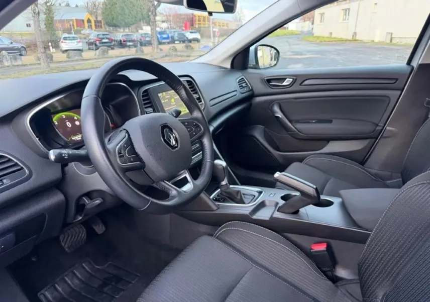 Vue intérieure côté conducteur de la Renault Mégane 2019, tableau de bord noir avec volant multifonction et écran central.