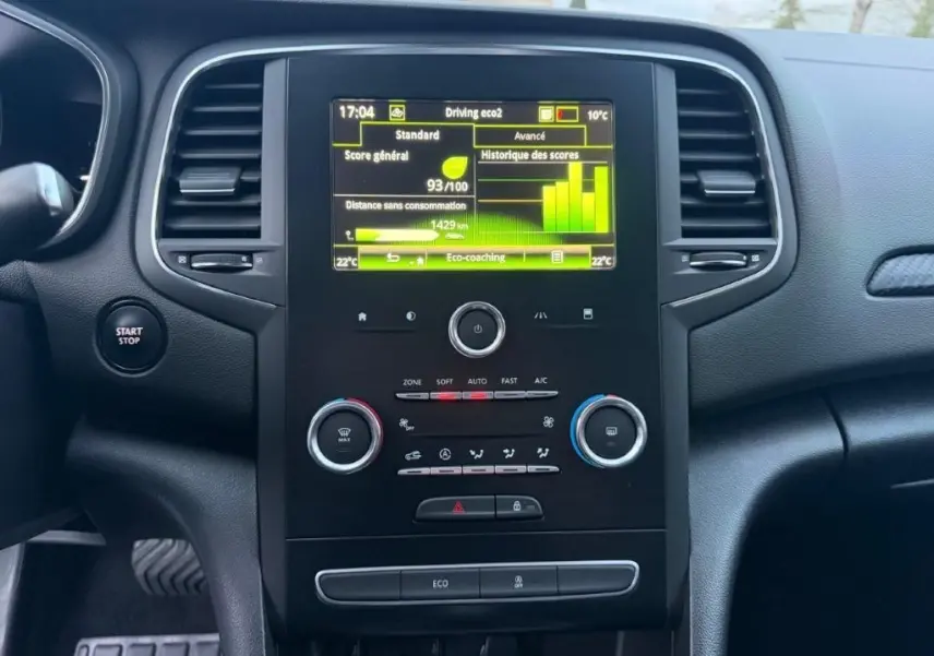 Vue rapprochée du tableau de bord de la Renault Mégane gris alu, avec écran tactile affichant l'eco-coaching et commandes climatisation.