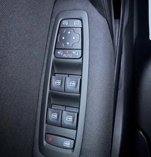 Gros plan sur les commandes de lève-vitres et rétroviseurs électriques côté gauche d'une Renault Mégane gris alu de 2019.