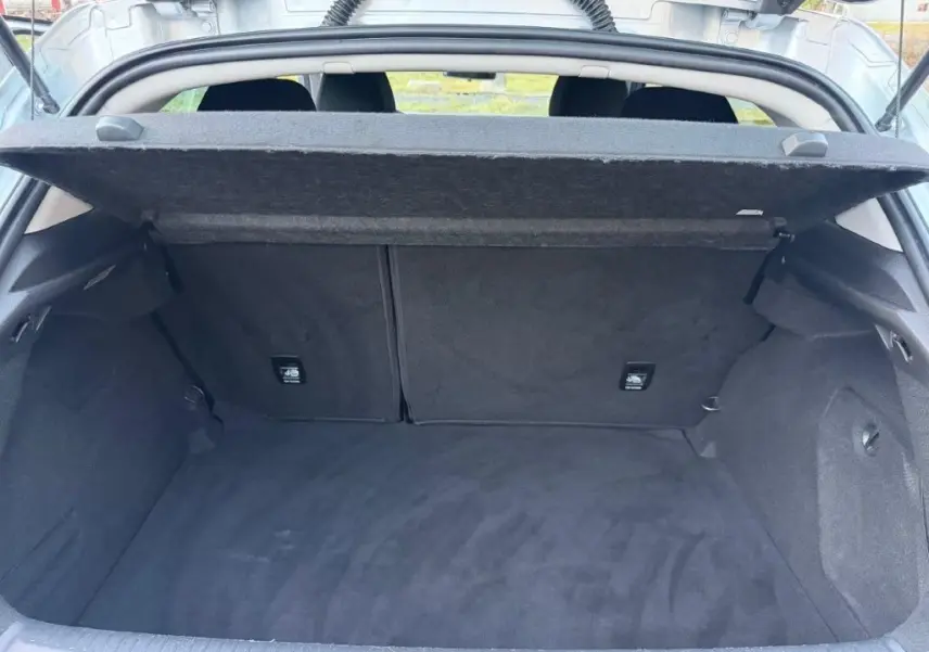 Coffre ouvert vu de l'arrière d'une Renault Mégane gris alu, montrant un espace de chargement propre et spacieux.