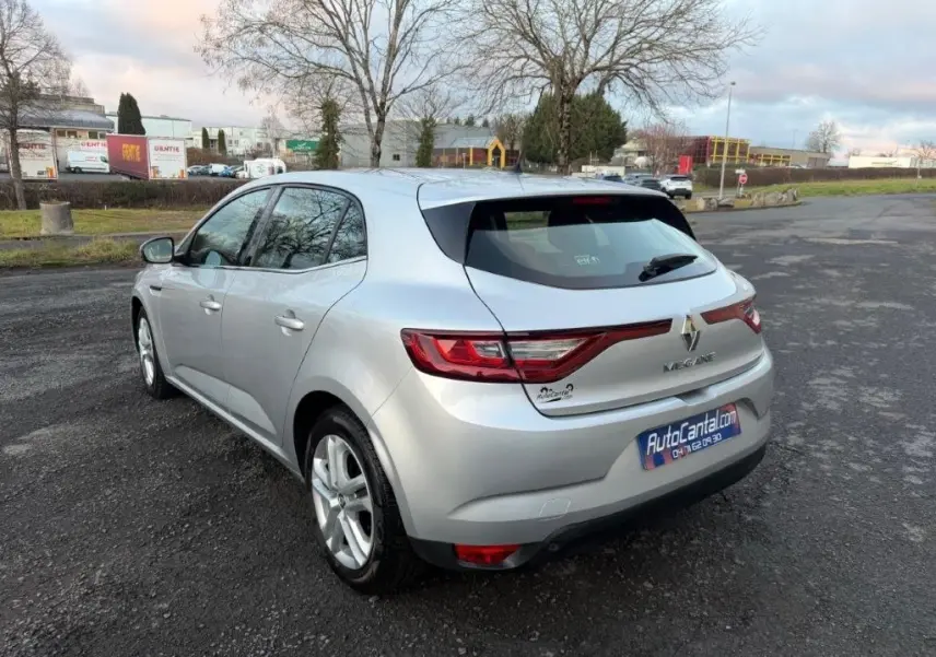 Renault Mégane gris alu vue 3/4 arrière droit sur parking, feux arrière LED et jantes alliage visibles.