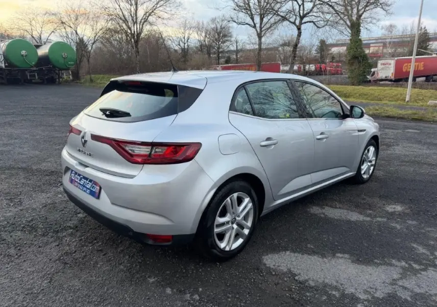 Renault Mégane gris alu vue 3/4 arrière droit sur parking, avec feux arrière LED et jantes alliage visibles.