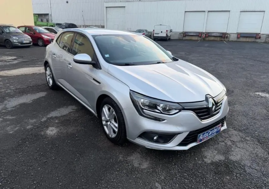 Renault Mégane gris alu vue 3/4 avant droit, avec phares LED et jantes alliage sur parking extérieur.