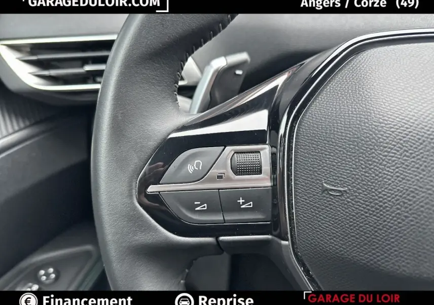 Gros plan sur le volant cuir noir du Peugeot 3008 blanc, avec commandes audio intégrées visibles à gauche.