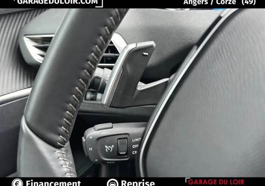 Gros plan sur le volant en cuir et les commandes de régulateur de vitesse du Peugeot 3008 blanc, intérieur côté conducteur.