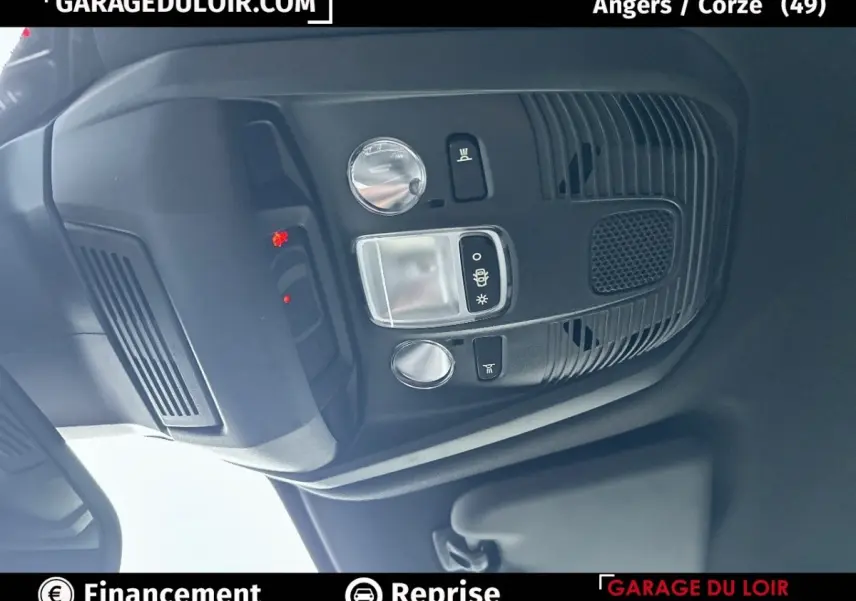 Vue rapprochée du plafonnier intérieur noir du Peugeot 3008 blanc 2024 avec commandes d’éclairage et haut-parleur intégré.