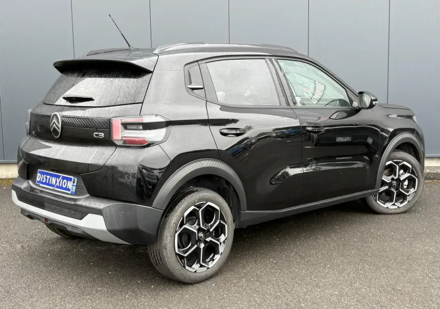Vue 3/4 arrière droite d'une Citroën C3 Turbo 100 Max noire Perla avec jantes alliage 17 pouces et barres de toit noires.