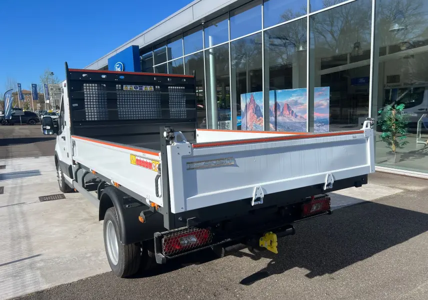 Ford Transit Chassis cabine blanc vu en 3/4 arrière avec benne relevée et coffre latéral visible.