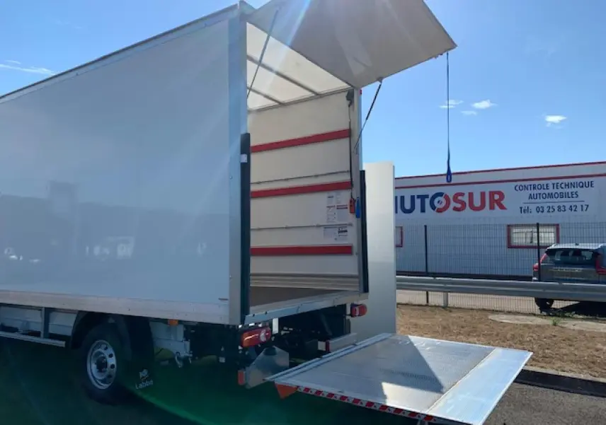 Vue arrière droite du FIAT Ducato blanc avec hayon élévateur déployé sous un ciel dégagé.