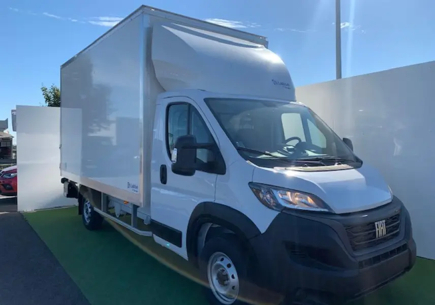 Fiat Ducato Fourgon blanc en 3/4 avant droit, avec caisse capucine et jantes acier 16 pouces visibles.