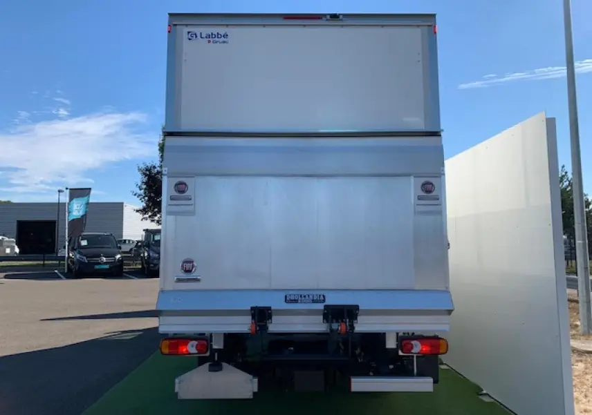 Vue arrière d'un FIAT Ducato Fourgon blanc avec hayon élévateur et marquages Labbé sur un parking.